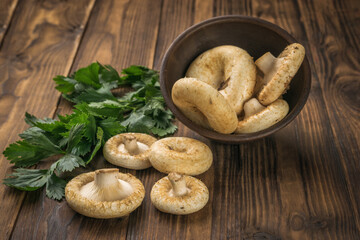 Forest mushrooms spilling out of the bowl on a wooden background.