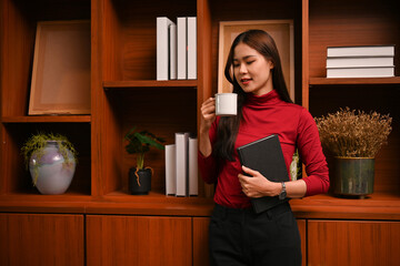 Beautiful Asian businesswoman sipping her morning coffee in her modern vintage office.