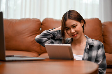 Pretty Asian young woman uses digital tablet to chat with her online friends