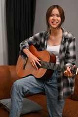 Portrait, A talented and hipster young Asian woman sings while playing her acoustic guitar