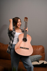 Hipster Asian woman with her acoustic guitar in her modern vintage living room.