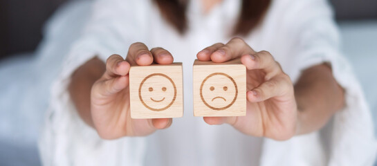 Woman holding smile and angry emotion face block. Customer choose Emoticon for user reviews....