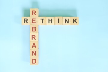 Rethink and rebrand business concept. Wooden blocks crossword puzzle flat lay in blue background.	