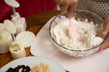Female hands making dough for mooncake, homemade cantonese moon cake pastry on baking tray before baking for traditional festival. Travel, holiday, food concept