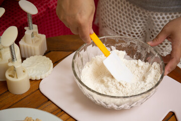 Female hands making dough for mooncake, homemade cantonese moon cake pastry on baking tray before baking for traditional festival. Travel, holiday, food concept