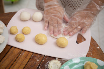 Female hands making dough for mooncake, homemade cantonese moon cake pastry on baking tray before...