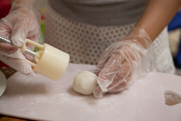 Making Mooncake. A mooncake is being moulded using plastic mould. The mould is being lifted, leaving the moulded mooncake on the board.