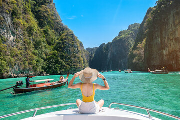 Woman tourist on boat trip, happy traveller relaxing at Pileh lagoon on Phi Phi island, Krabi, Thailand. Exotic landmark, destination Southeast Asia Travel, vacation and holiday concept - obrazy, fototapety, plakaty