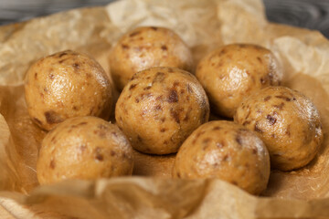 Useful homemade sweets.  Coconut flour with dark chocolate.  In the form of balls.  On craft paper.