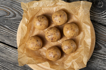 Useful homemade sweets.  Coconut flour with dark chocolate.  In the form of balls.  On pine boards.