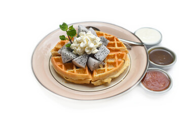 Belgium waffles with sliced dragon and ice cream on a plate with chocolate toping and fruit sauce