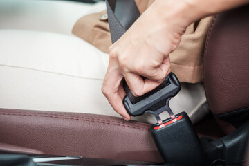 woman driver hand fastening seat belt during sitting inside a car and driving in the road. safety, trip, journey and transport concept
