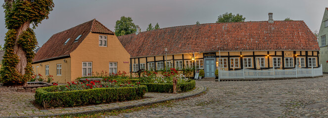 Cobbled square with roses and a vintage timber framed hotel in the dusk evening light