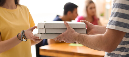 Young woman receiving boxes with tasty pizzas from courier, closeup
