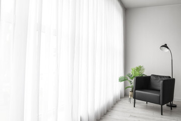 Interior of living room with black armchair, standard lamp and palm tree