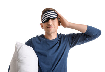 Young man with sleeping mask and pillow on white background