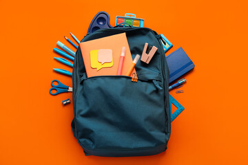 School backpack with stationery on red background