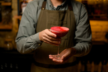 close-up view of male hands gently holding wine glass with red alcoholic drink