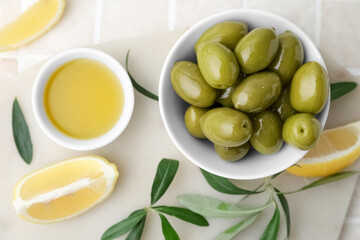 Bowls with green olives, oil and lemon slices on color tile