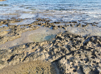 The coast of the Mediterranean Sea, long frozen lava, in the recesses of which water splashes.