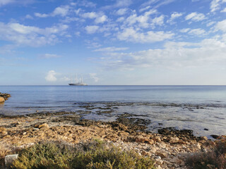 The largest sailing yacht in the world, an eight-deck motorsailer on the Mediterranean coast against a blue sky with clouds.