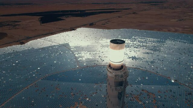 Solar power tower focused sunlight for movable mirrors at the desert in a cloudless day- close up tilt down drone dolly in shot