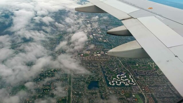  Scenic shot from plane window of the airplane wing while flying over the city at daytime.