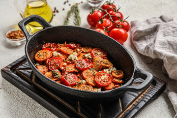 Wooden board with baking dish of tasty baked vegetables on light background