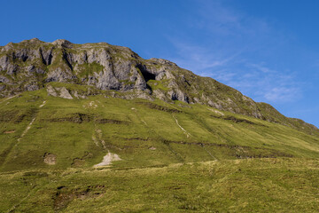Mountains and green fields with sheep in Gleniff horseshoe drive, county Sligo, Ireland. Warm sunny day. Clean blue sky. Popular tourist location with amazing nature scenery. Irish landscape.