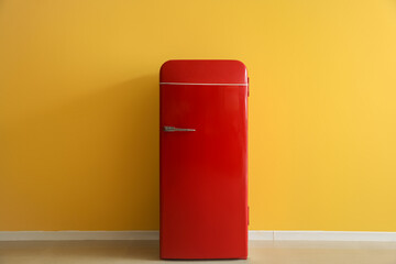 Stylish retro fridge near yellow wall