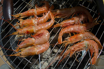 evocative close-up image of king prawns on the BBQ grill ready to be cooked
