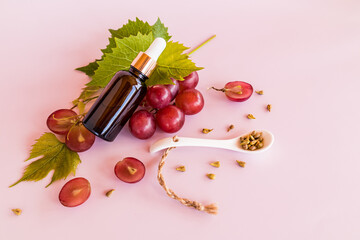 top view of a cosmetic bottle with a pipette and ripe grape berries with organic natural cosmetics....