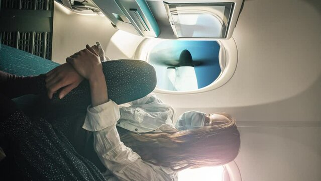 A young woman wearing face mask during travel with airplane , New normal journey after covid-19 pandemic concept. Cinemagraph. Still picture with moving propeller
