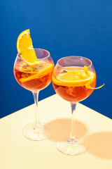 Concept of summer cocktail, Aperol Spritz on beige table against blue background