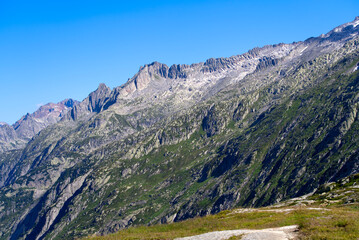 Fototapeta premium Scenic view of mountain panorama seen from summit of Swiss mountain pass Grimsel on a sunny summer day. Photo taken July 3rd, 2022, Grimsel Pass, Switzerland.