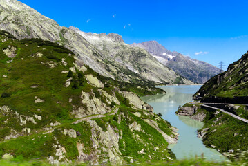 Scenic view of dam lake with mountain panorama in the background at Swiss mountain pass Grimsel on a sunny summer day. Photo taken July 3rd, 2022, Grimsel Pass, Switzerland.