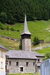 Fototapeta na wymiar Roman style stone church named St. Kolumban at Swiss mountain village on a sunny summer day. Photo taken July 3rd, 2022, Andermatt, Switzerland.