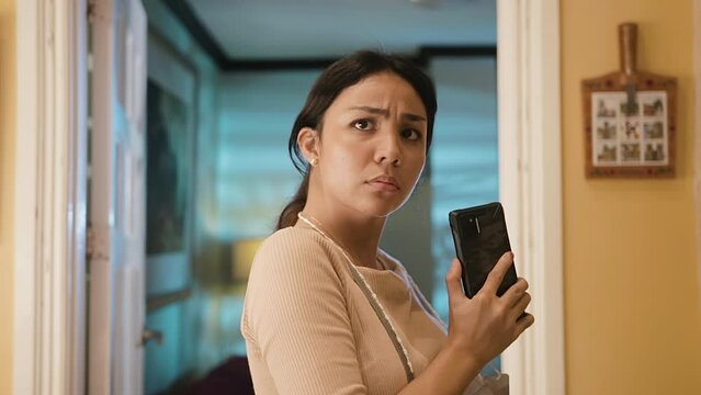 Zoom on Shot Asian Woman Talking to Mobile Phone that is Distracted and Looks at Camera Questioningly and Suspiciously 