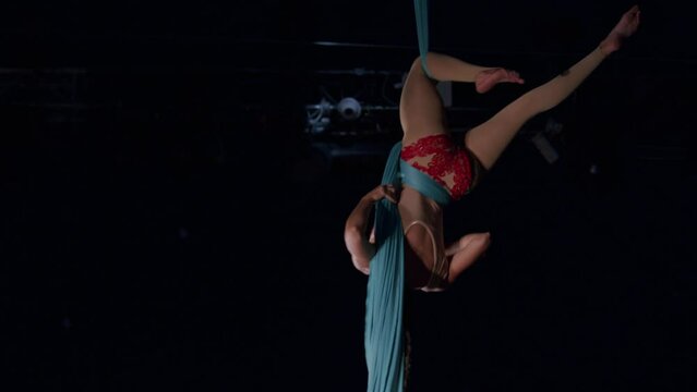 Aerial silk acrobat dancing and spinning with tissue rope