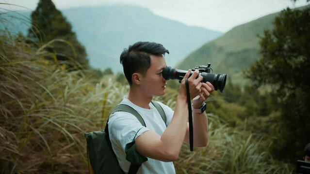 A young Asian male photographer in a white T-shirt and a backpack is taking photographs of nature in the mountains in northern Taiwan. Shot on URSA Mini Pro 4.6K G2