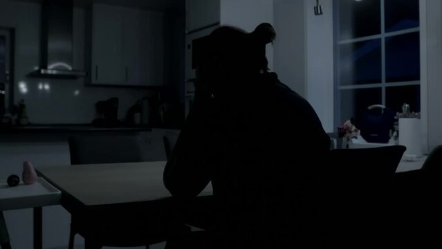 Sad Depressed Woman sits at kitchen table At Home awake at night