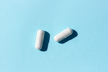 Two white pills on blue background. Medicine, healthcare concept. Top view Flat lay