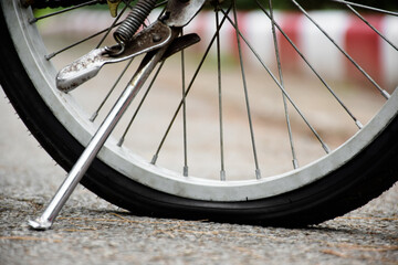 Closeup rear flat wheel of vintage bike on pavement in the evening of the day, sunset light edited, soft and selective focus