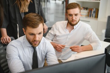 Smiling business people sitting at a desk in front of a laptop computer