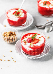 Healthy summer cream cheese dessert with strawberry puree fresh berries, granola and sprig of thyme in glass bowls. Vegan healthy breakfast. Homemade sweet food concept.