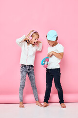 Portrait of two young smiling kids Play more fun together pink color background