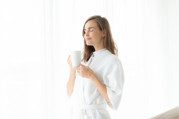 beautiful woman drinking coffee or milk in the morning by the window. view from outside. She drinking milk after wake up in the morning