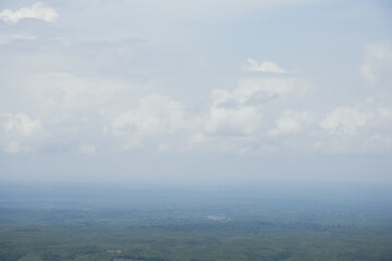 Aerial landscape view with a drone of meadow and cloudy sky horizon. Beautiful natural view of green fields and sky. Foggy weather drone shot of a hilly jungle area and sky horizon.