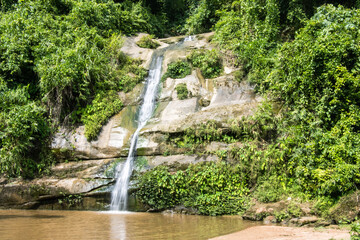 Fototapeta na wymiar Beautiful waterfall photography with green trees. rocky hill waterfall photo with small river flow in a tropical forest. Beautiful natural view with a rocky mountain and waterfall.