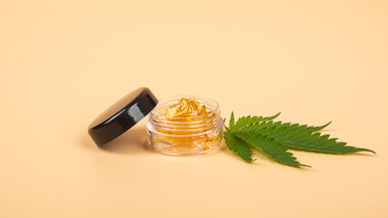 yellow cannabis wax resin and green leaf on yellow background.